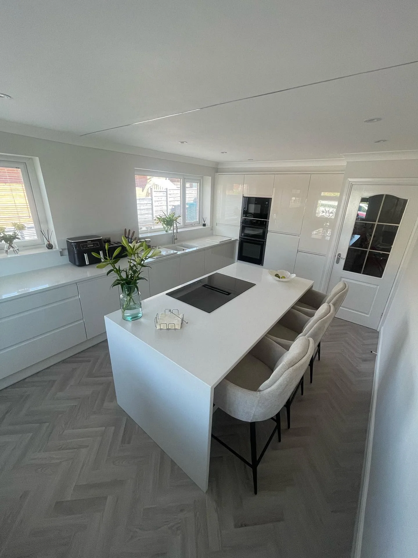 White handleless kitchen island with breakfast bar seating installed by Tailormade Kitchens & Bedrooms